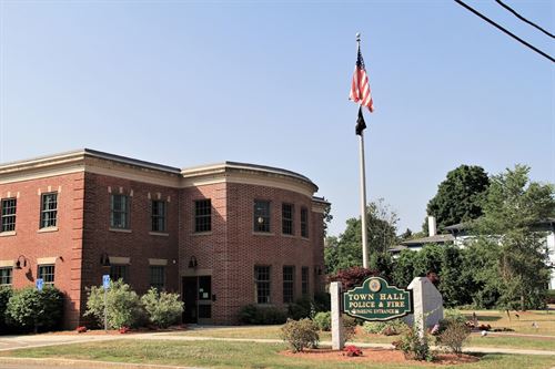 wrentham town hall with a flag pole and american flag flying